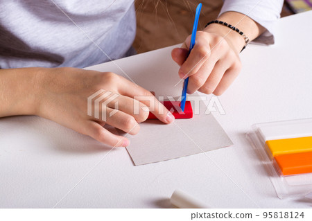 Children's hands cut polymer clay with a modeling tool. Handmade and leisure. 95818124