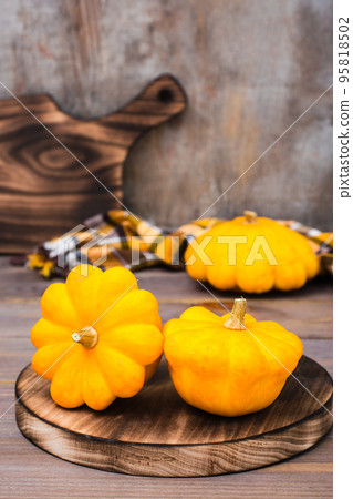 Three fresh bush pumpkin on a cutting board on wooden background Three fresh bush pumpkin on a cutting board on wooden background 95818502