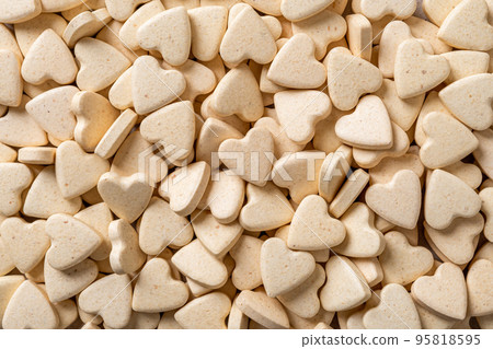 Pet supplement tablets background. Macro texture of heart shaped pills for cats and dogs. 95818595