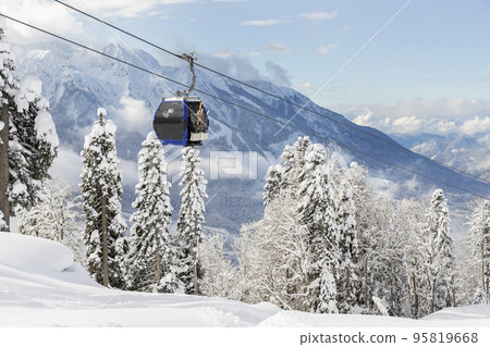 New modern spacious big cabin ski lift gondola against snowcapped forest tree and mountain peaks covered in snow landscape in luxury winter alpine resort. Winter leisure sports, recreation and travel New modern spacious big cabin ski lift gondola against snowcapped forest tree and mountain peaks covered in snow landscape in luxury winter alpine resort. Winter leisure sports, recreation and travel 95819668