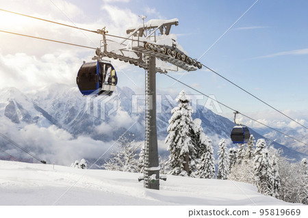 New modern spacious big cabin ski lift gondola against snowcapped forest tree and mountain peaks covered in snow landscape in luxury winter alpine resort. Winter leisure sports, recreation and travel 95819669