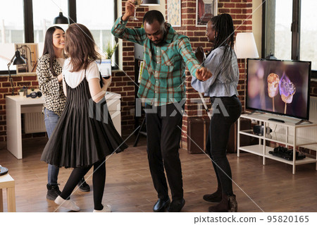 Young adult african american male having fun, chilling, dancing, smiling, laughing, enjoying social life accompanied by women at apartment party. Multicultural people hanging around. Young adult african american male having fun, chilling, dancing, smiling, laughing, enjoying social life accompanied by women at apartment party. Multicultural people hanging around. 95820165