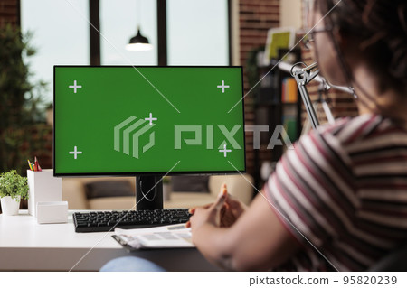 Remote worker computer with green screen at home office table, focus on pc monitor mock up. Woman working, sitting at workplace desk, employee professional equipment with chroma key display Remote worker computer with green screen at home office table, focus on pc monitor mock up. Woman working, sitting at workplace desk, employee professional equipment with chroma key display 95820239
