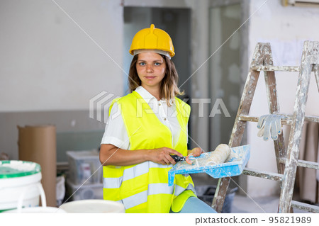 Cheerful woman builder holding paint roller and tray, home improvement works 95821989