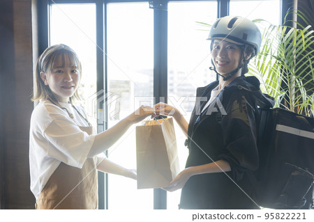 Restaurant clerk asking a delivery person for food delivery 95822221