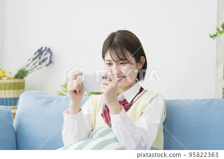 High school student watching a video on a smartphone at home 95822363