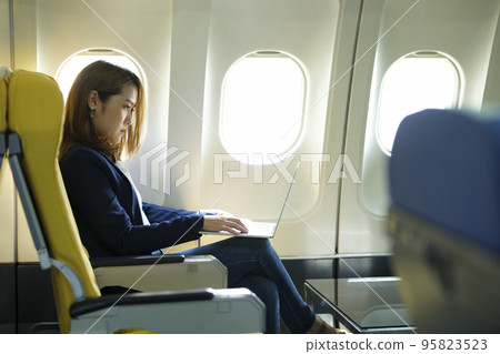 Business woman working on laptop while sitting in airplane. Business woman working on laptop while sitting in airplane. 95823523