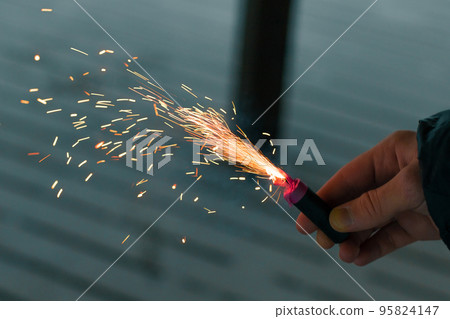 Burning Firecracker with Sparks. Guy Holding a Petard in a Hand 95824147