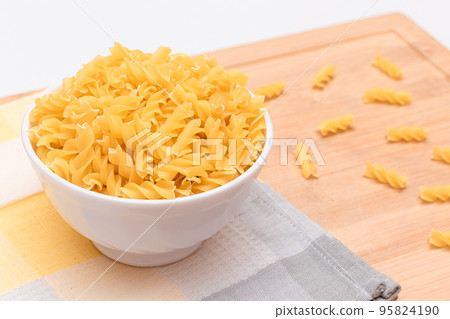 Uncooked Fusilli Pasta in White Bowl on Wooden Board Uncooked Fusilli Pasta in White Bowl on Wooden Board 95824190