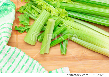Fresh Celery Stem and Chopped Celery Sticks on Wooden Cutting Board 95824230