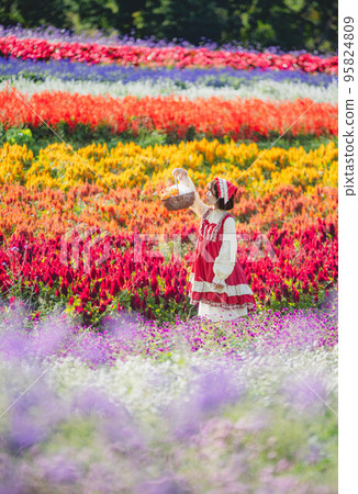 A flower garden and a woman dressed as Little Red Riding Hood 95824809