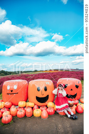 A woman dressed up and photographed with a Halloween pumpkin 95824819