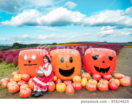 A woman dressed up and photographed with a Halloween pumpkin 95824820