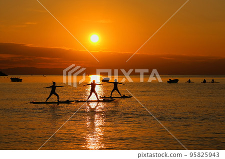 Zushi beach at dusk, silhouettes of women enjoying SUP yoga Zushi beach at dusk, silhouettes of women enjoying SUP yoga 95825943