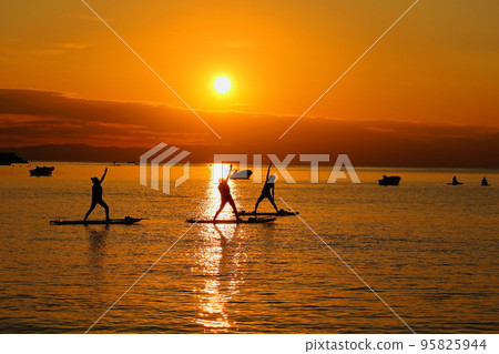 Zushi beach at dusk, silhouettes of women enjoying SUP yoga Zushi beach at dusk, silhouettes of women enjoying SUP yoga 95825944