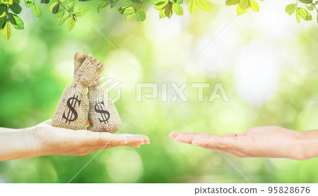 A women hands hold a money bags in the public park and men for loans to planning savings money of coins buy a home A women hands hold a money bags in the public park and men for loans to planning savings money of coins buy a home 95828676