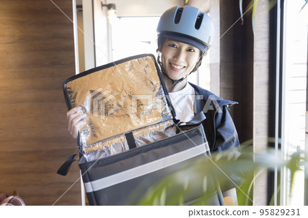 Food delivery A female delivery worker who comes to pick up the product and opens the cooler bag Food delivery A female delivery worker who comes to pick up the product and opens the cooler bag 95829231