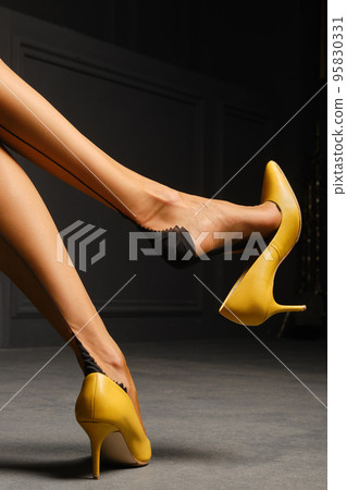 View in profile of an unrecognizable woman swinging high heel shoe on her foot View in profile of an unrecognizable woman swinging high heel shoe on her foot 95830331