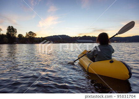 Adventurous Woman Kayaking on an Inflatable Kayak in the Pacific Ocean. Sunset Sky 95831704