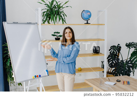 Professional business trainer near flip chart board in a spacious classroom. Space for text Professional business trainer near flip chart board in a spacious classroom. Space for text 95832212