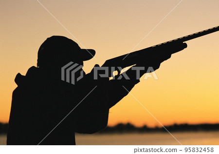 Hunter pointing gun at the sky - silhouette Hunter pointing gun at the sky - silhouette 95832458