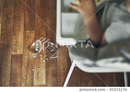 A small baby on a high chair dropped a cup of noodle soup on the wooden floor. The transparent plate is divided into two parts. Noodles in the form of figures. The table is dirty. High quality photo A small baby on a high chair dropped a cup of noodle soup on the wooden floor. The transparent plate is divided into two parts. Noodles in the form of figures. The table is dirty. High quality photo 95833239