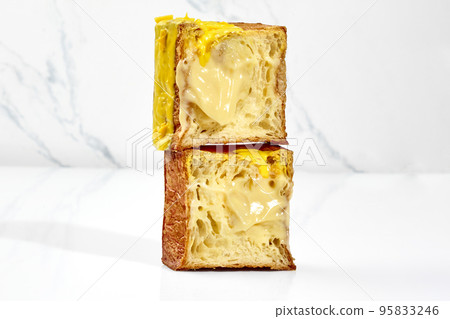 Sliced flaky cubic croissant with vanilla custard filling, yellow glaze and chocolate chips 95833246