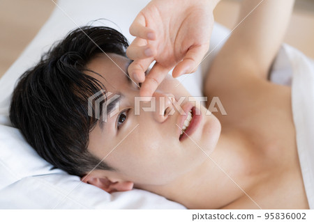 Close-up of a young man's face waking up in bed 95836002