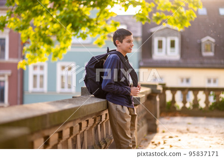 Joyous teen with the backpack on his back standing outside Joyous teen with the backpack on his back standing outside 95837171