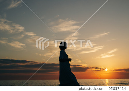 woman walking on the beach at sunset 95837414