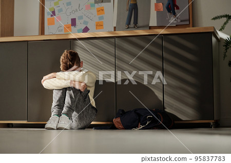 Helpless secondary school pupil sitting on the floor of classroom 95837783