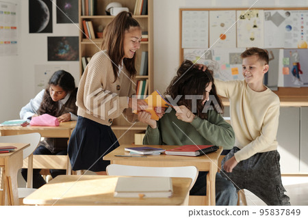 Two cruel classmates fighting with schoolboy and taking his copybook Two cruel classmates fighting with schoolboy and taking his copybook 95837849