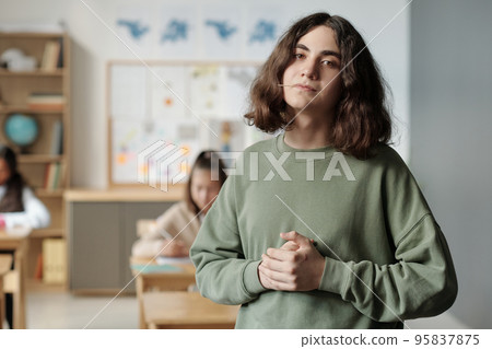 Pre-teen confident and impudent guy with toothpick in mouth looking at camera 95837875