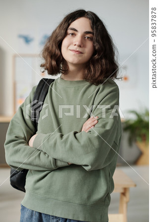 Youthful secondary school pupil in grey sweatshirt standing in classroom Youthful secondary school pupil in grey sweatshirt standing in classroom 95837878