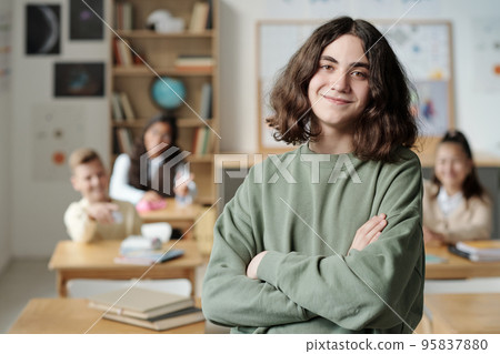 Smiling pre-teen secondary school learner in sweatshirt crossing arms by chest Smiling pre-teen secondary school learner in sweatshirt crossing arms by chest 95837880