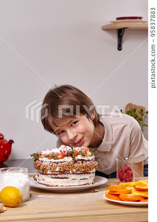 Little boy is making a homemade cake with an easy recipe at kitchen against a white wall with shelves on it. Little boy is making a homemade cake with an easy recipe at kitchen against a white wall with shelves on it. 95837883
