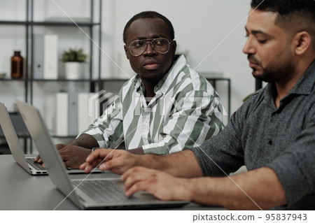 Black man looking at colleague saying him something unpleasant and offensive 95837943