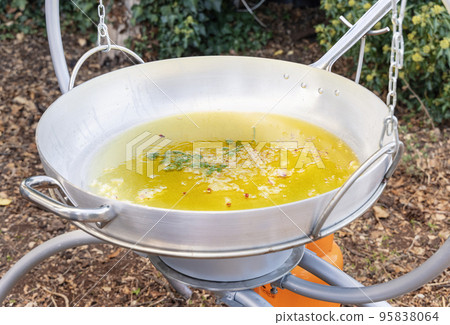 Chopped Garlic and onion frying with olive oil  in a big frying pan outdoor close up 95838064