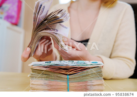 women's hands hold a stack of rubles tied with a rubber band. women's hands hold a stack of rubles tied with a rubber band. 95838674