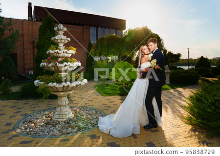 happy newlyweds. groom and bride in traditional wedding clothes in park. sunset. 95838729