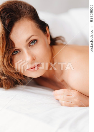 sexy naked brunette woman lying in bed. women's health and attractiveness. 95839003