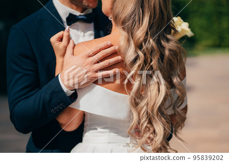 newlyweds. groom and bride in traditional wedding clothes cuddling in park 95839202