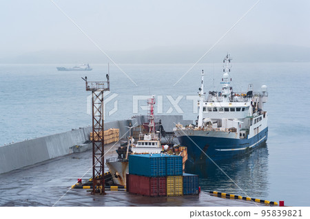fishing boat at the pier in the harbor on the shore of a cloudy sea fishing boat at the pier in the harbor on the shore of a cloudy sea 95839821