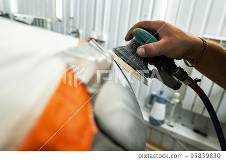 Close up of car cleaner polishing headlight with polish machine 95839830