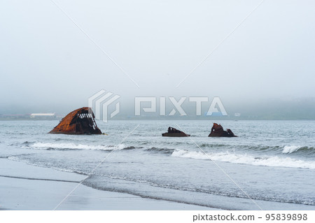 rusty shipwreck, remains of a ship washed ashore against a foggy seashore rusty shipwreck, remains of a ship washed ashore against a foggy seashore 95839898