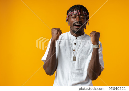 Young african man standing over yellow background doing winner gesture Young african man standing over yellow background doing winner gesture 95840221