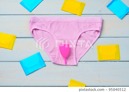 Menstrual cup and panties on wooden background. Menstrual cup and panties on wooden background. 95840512