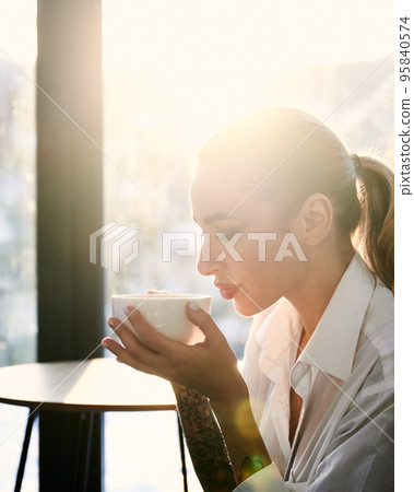 Close up silhouette of young woman with tattoos on hands drinking hot tea, enjoying weekends inside house. Close up silhouette of young woman with tattoos on hands drinking hot tea, enjoying weekends inside house. 95840574