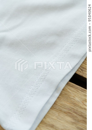 Close up of white T-Shirt on wooden background Close up of white T-Shirt on wooden background 95840624