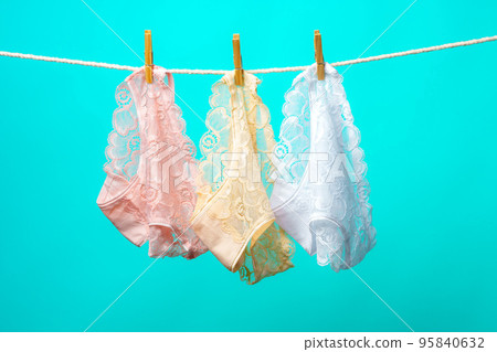 Female panties hanging on rope against blue studio background Female panties hanging on rope against blue studio background 95840632